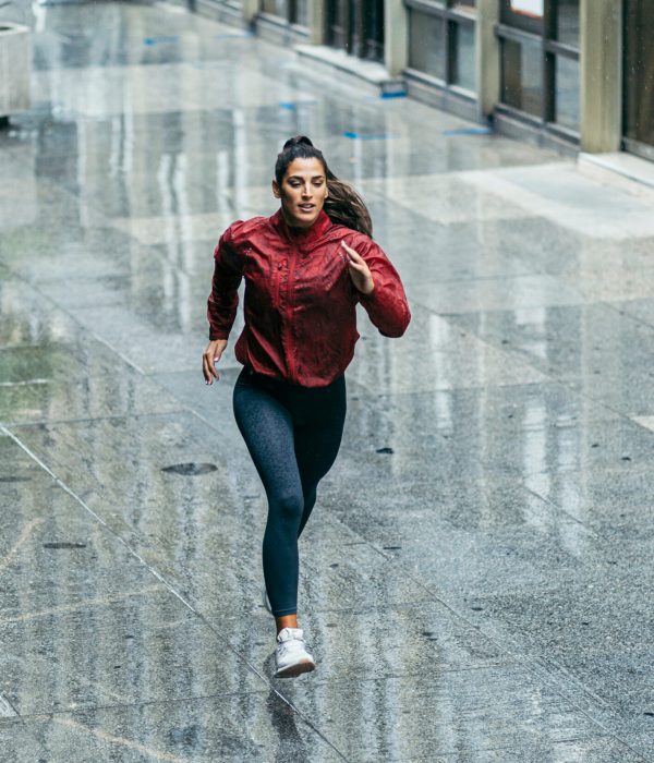 Sportswoman,Running,Wearing,A,Red,Windbreaker,,Black,Leggings,And,White